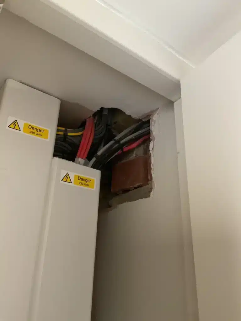 Cabling and an opening in the lining above the electrical trunking.
