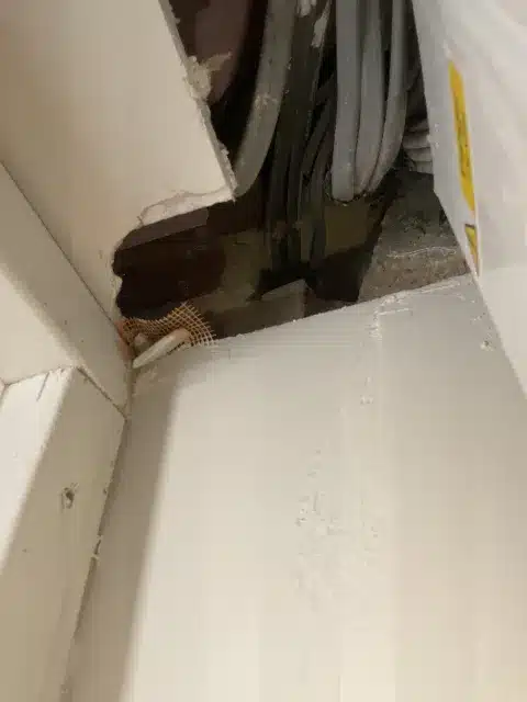 Close-up of a cable penetration through the cupboard lining.